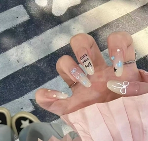 Detail of pink gradient press-on nails with white bows, stars, and rhinestones