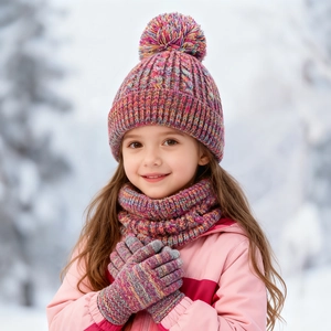 Kids winter knit set with thick rainbow pompom hat, scarf and gloves in snowy setting