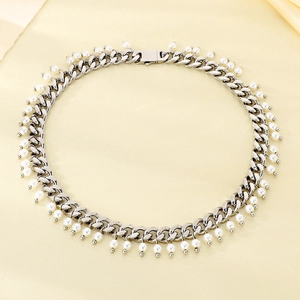 Detail of 9mm silver Cuban chain necklace with white pearls on soft silk background