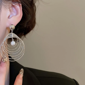 Macro view of multi-layer circular silver earrings with a white pearl pendant