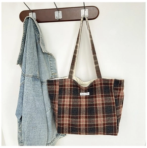 Detail of red-brown checkered tote bag made of cotton linen featuring a small white label