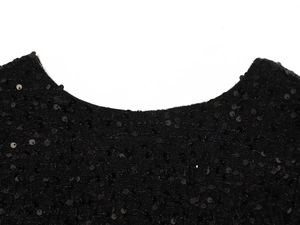 Detailed macro view of the black sequin neckline and knit fabric texture on a woman's top