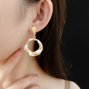 Close-up of vintage gold and white twisted geometric earrings worn by a model