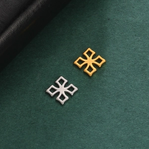Detail of hollow cross charms in gold and silver finish on textured green background