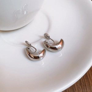 Macro di orecchini a clip a goccia argento su vassoio bianco con chiusura a spirale