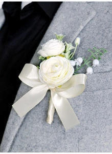 Detail of white artificial flowers boutonnieres with silk ribbon on grey suit lapel