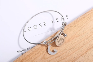 Detail of adjustable silver stainless steel bracelet with moon and star charm pendants