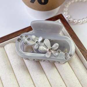 Close-up of acetic acid flower hair claw clip with rhinestones in a jewelry tray