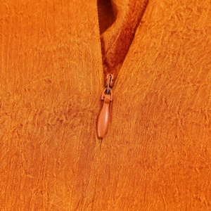 Close-up of a hidden zipper on orange satin fabric with elegant pleated texture