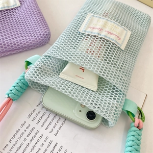 Detailed macro view of mint green mesh phone pouch showing interior space and woven strap