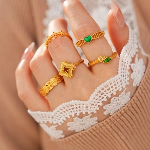 Gros plan de bagues vintage dorées avec zircon vert sur main à manche en dentelle