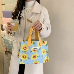 Detail of portable canvas lunch bag featuring vibrant sunflower prints and yellow handles