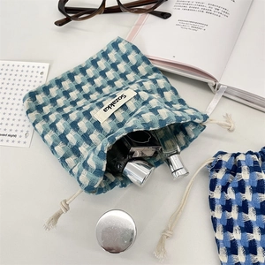 Détail du sac de rangement à carreaux bleus montrant la texture tissée et les cosmétiques