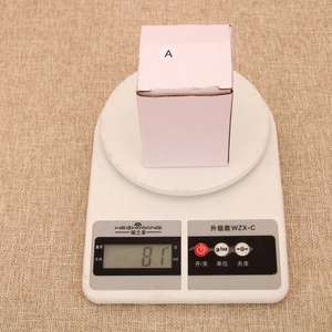 Detailed view of Christmas resin house ornament weighing 81g on a digital scale