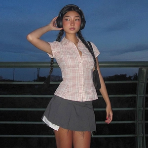 Y2K style pink plaid short sleeve shirt paired with a dark grey pleated mini skirt outdoor