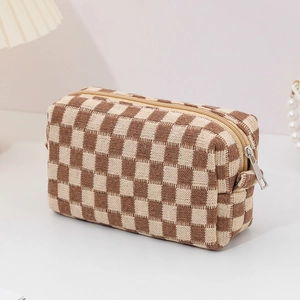 Detail view of checkerboard knit makeup bag with smooth metal zipper and beige fabric