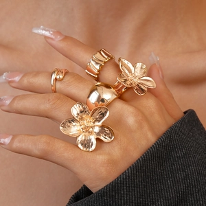 Macro shot of a five-piece set of gold-toned rings with 3D floral and textured patterns