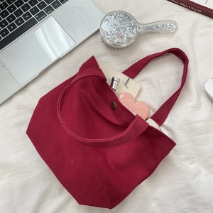 Detail view of burgundy canvas lunch bag featuring internal storage and magnetic metal clasp