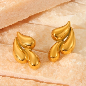 Gros plan de boucles d'oreilles en forme de feuille dorée 18 carats sur marbre rose
