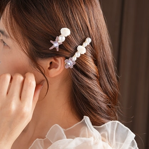 Détail de barrettes étoile de mer et fleurs avec strass et perles sur les cheveux