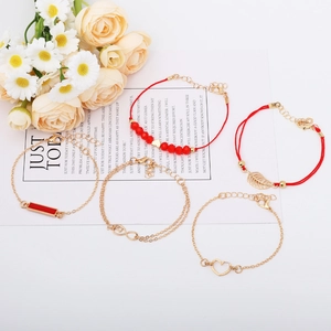 Detail of red bead and gold leaf charm bracelets set on a floral aesthetic background