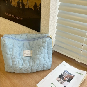 Quilted floral cosmetic bag in soft light blue with spacious zipper storage design