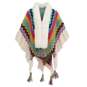 Detailed view of colorful knitted poncho featuring faux fur collar and fringe tassels