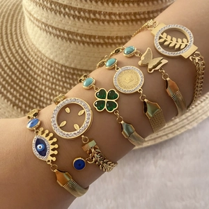 Détail de bracelets bohèmes dorés avec charms oeil et trèfle portés par un mannequin