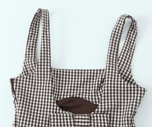Detail of checkered shoulder straps and side zipper on a stretch plaid top
