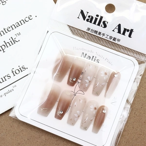 Floral coffee gradient press-on nails with silver rhinestones on a warm textured background