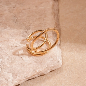 Detailed macro view of triple-layered golden ear cuff resting on a textured natural stone