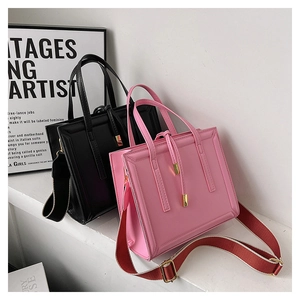 Detail view of square crossbody bags in black and pink with wide striped shoulder straps