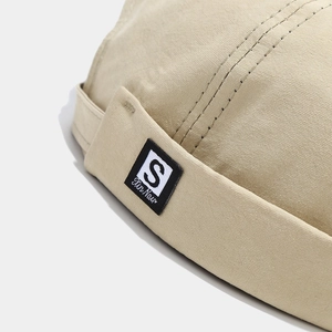 Detail shot of khaki docker hat with fabric texture and S letter woven label