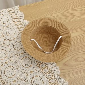 Detail of flat-top straw hat interior with elastic strap and fine woven texture