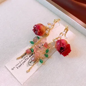 Preserved rose bud earrings with pearls and pink crystals on beige fabric