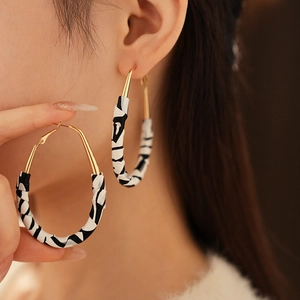 Gros plan de créoles dorées avec tissu imprimé zèbre portées par un mannequin