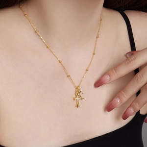 Detail of gold-plated double cross necklace with inlaid stones on model collarbone