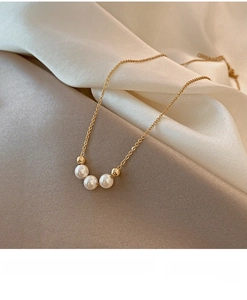 Detailed shot of gold pearl necklace on champagne silk with lobster clasp and charm