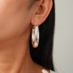 Close-up of chunky silver geometric hoop earrings worn by a model for a stylish commute