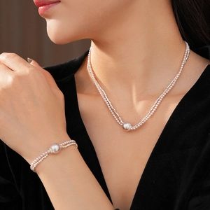 Close-up of polished silver pearl pendant necklace and bracelet set on a model