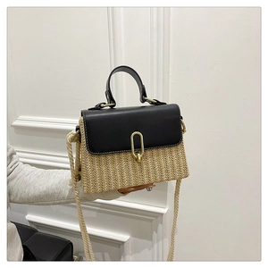 Detail view of woven straw and black leather crossbody bag with rope strap