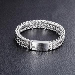 Close-up of mens stainless steel woven chain bracelet with sturdy buckle on black leather
