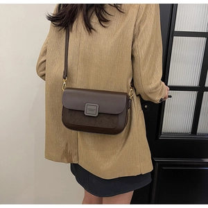 Detail of vintage brown leather and suede crossbody bag showing metal buckle and fit