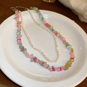 Close-up of layered butterfly necklace with colorful crystals and white rice pearls