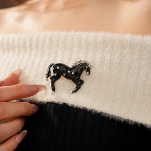 Close-up of a vintage horse brooch with black enamel and diamonds on knit fabric