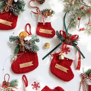 Festive red knit Christmas stocking with pine cones, cinnamon, and bells on white background
