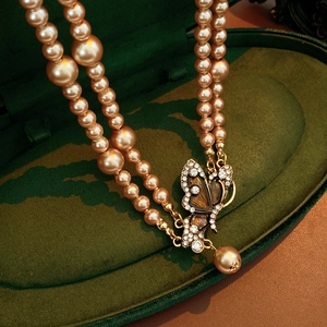 Detail of vintage champagne pearl necklace with rhinestone butterfly pendant in velvet box