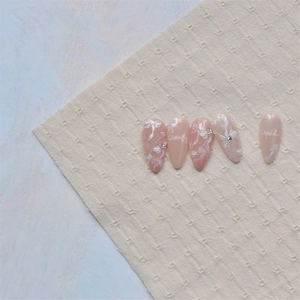 Close-up of pink press-on nails with white butterfly floral art and small rhinestones
