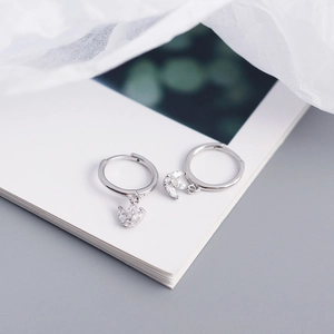 Detail of silver S925 crown hoop earrings with marquise zirconia charms on a white book