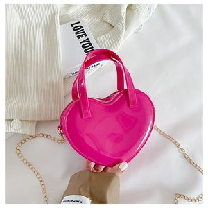 Macro shot of rose red heart-shaped jelly bag with glossy finish and gold chain strap